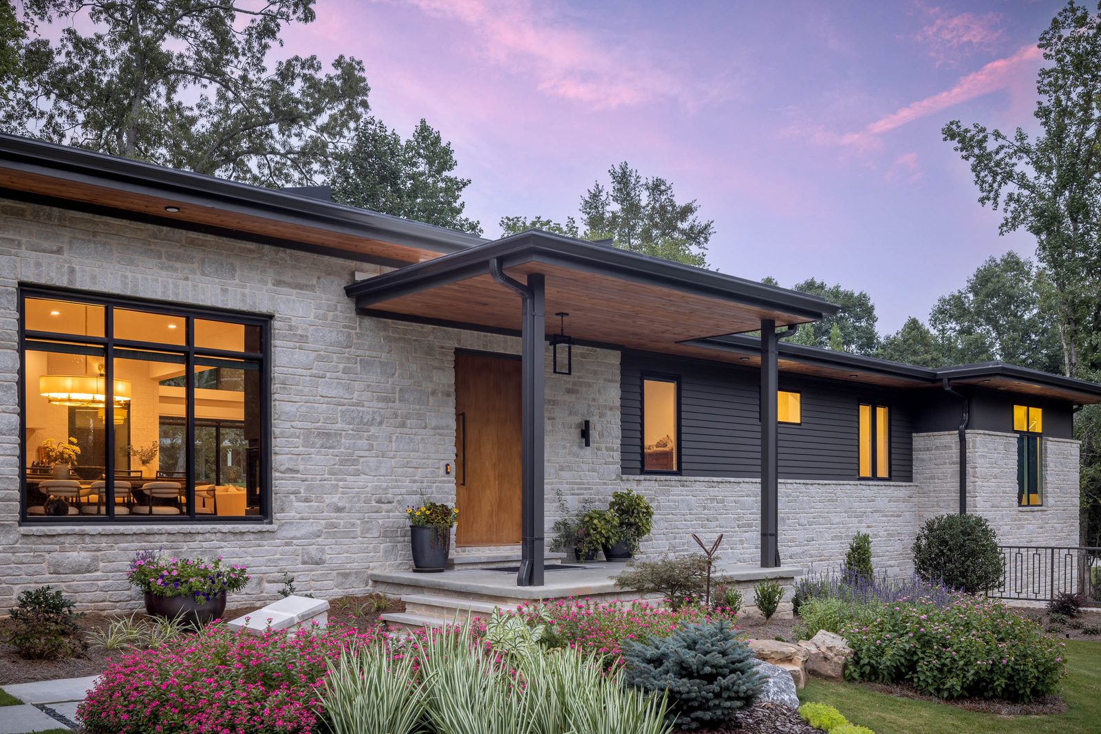 Front elevation at dusk with the flowering beds lit — The Ortiz Home, custom home built by Ironwood Construction Group in Sugar Hill, Georgia