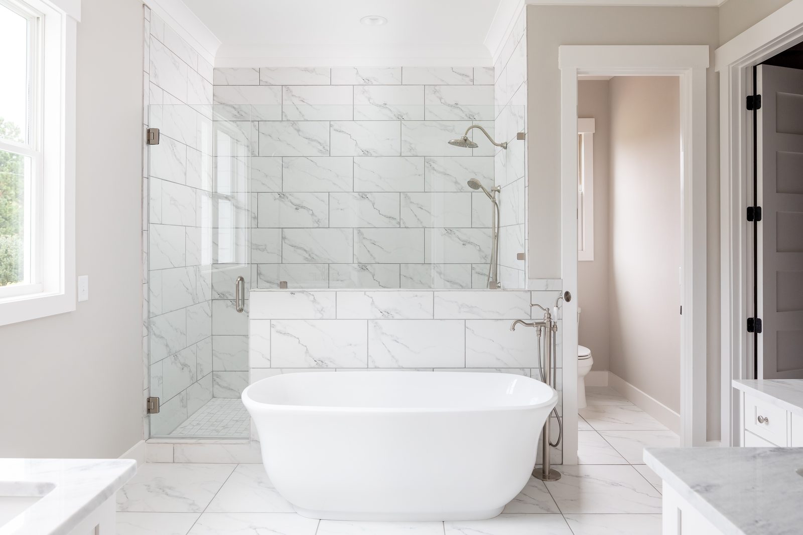 Primary bath with freestanding soaking tub and marble-tiled shower — Shadburn Ferry, custom home built by Ironwood Construction Group in Buford, Georgia
