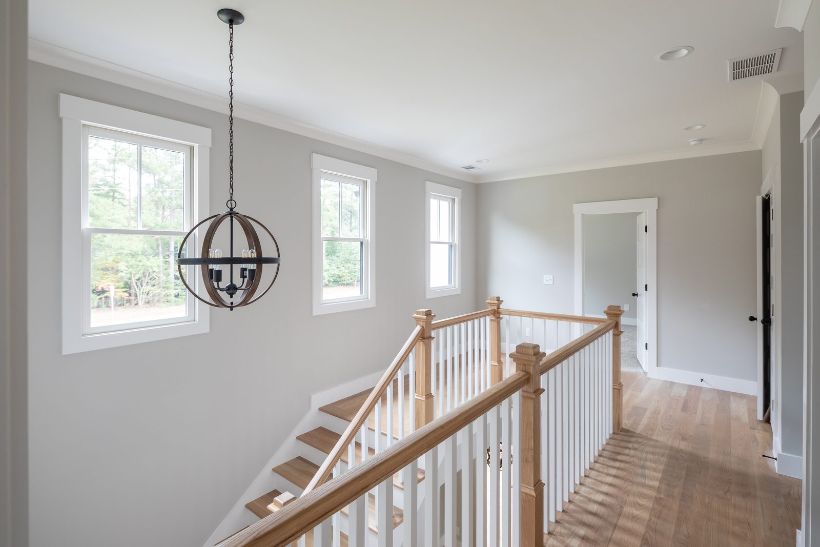 Upstairs landing with wood stair rail and lantern pendant — Shadburn Ferry, custom home built by Ironwood Construction Group in Buford, Georgia